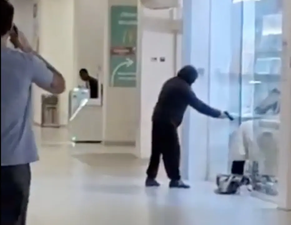 Instante del violento atraco a la joyer&iacute;a del centro comercial Madrid Sur, en Puente de Vallecas, donde uno de los encapuchados amenaza a una trabajadora mientras sus compinches destrozaban las vitrinas para llevarse las joyas.