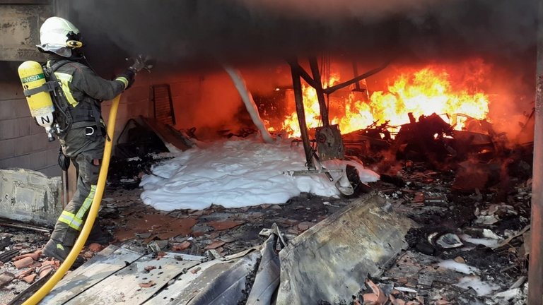 Bomberos del Servicio de Emergencias 112 del Gobierno de Cantabria extinguen un incendio en un garaje en Los Corrales de Buelna.