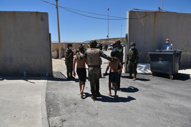 Archivo - Un militar del ejército español y un agente de la Guardia Civil ayudan a dos menores migrantes procedentes de Marruecos