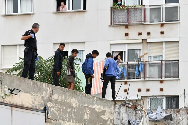 Un policía nacional trabaja para que un grupo de menores migrantes abandone el tejado de una nave industrial en Ceuta