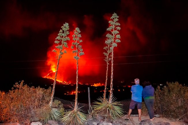 GRAF2426. LOS LLANOS DE ARIADNE (LA PALMA), 14/10/2021.- Una pareja vecinos de Los Llanos de Aridane observan como la colada se adentran en el barrio de La Laguna en la madrugada del jueves. El Plan de Emergencias Volcánicas de Canarias (Pevolca) ha determinado una nueva evacuación por la previsión de avance de la colada de lava del volcán de Cumbre Vieja, en La Palma, que discurre más al noroeste y que afecta a entre 250 y 300 vecinos, informaron a Efe fuentes del Gobierno de Canarias. EFE/ Miguel Calero
