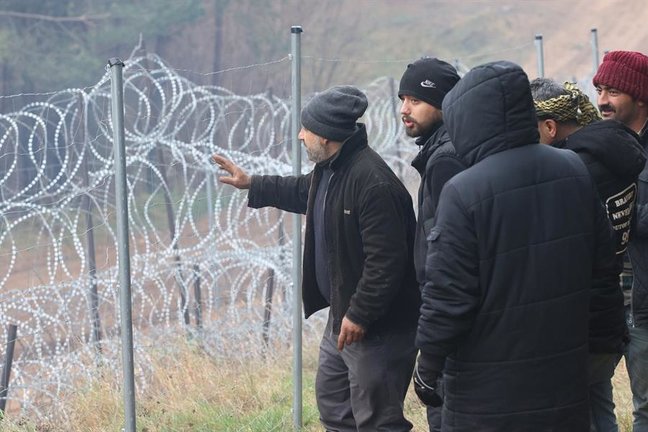Los migrantes acercándose a una valla reforzada con alambre de espino cerca de su campamento en la frontera entre Bielorrusia y Polonia en la región de Grodno, Bielorrusia, 10 de noviembre de 2021. Cientos de refugiados que quieren obtener asilo en la Unión Europea llevan tres días atrapados a bajas temperaturas en la frontera. (Bielorrusia, Polonia) EFE/EPA/LEONID SCHEGLOV/BELTA