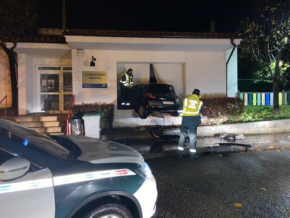 Los agentes de la Guardia Civil junto al vehículo empotrado en el Consultorio Médico de Cudón, en Miengo. / ALERTA