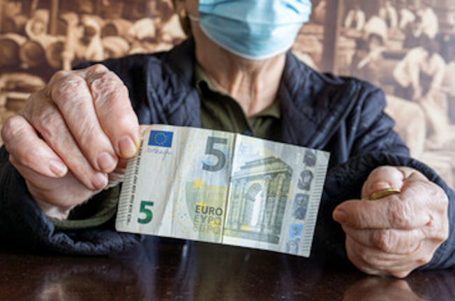 Una pensionista enseña un billete de cinco euros. / ALERTA