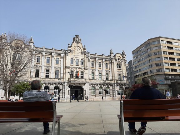 Dos personas sentadas en la plaza del Ayuntamiento de Santander. / ALERTA