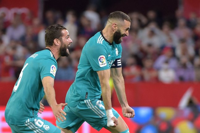 Real Madrid's French forward Karim Benzema (R) celebrates after scoring a goal during the Spanish League football match between Sevilla FC and Real Madrid CF at the Ramon Sanchez Pizjuan stadium in Seville on April 17, 2022. (Photo by CRISTINA QUICLER / AFP)