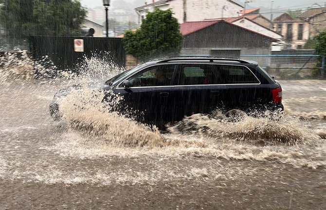 Un coche circula por una calle de Oviedo que se encuentra inundada tras las últimas lluvias registradas en la región. Todoel Principado, salvo la franja litoral, se encuentra hoy en alerta amarilla ante el riesgo de fuertes tormentas y precipitaciones que pueden alcanzar los 15 litros en una hora a partir del mediodía y que pueden presentarse también en forma de granizo. EFE/Paco Paredes