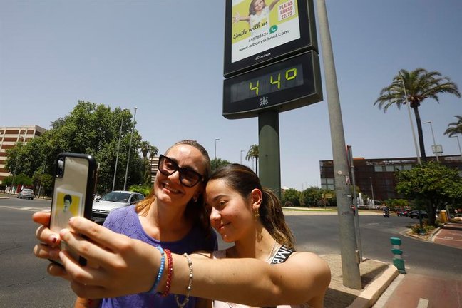Varios turistas se fotografían junto a un termómetro que marca 44 grados, este domingo en Córdoba. EFE/Salas