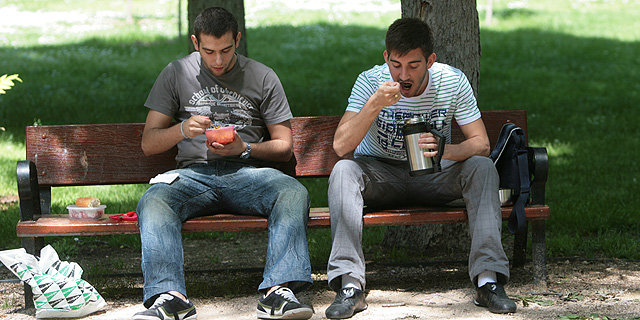 Dos jóvenes comiendo en un parque.