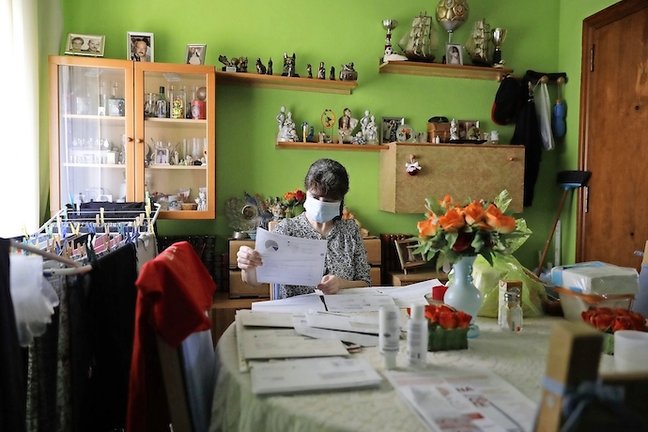 Una mujer revisa en su casa las facturas de la luz, agua y gas que debe abonar. / Ferran Nadeu