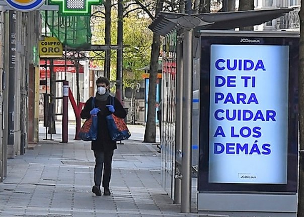 Una persona pasea junto a una parada de autobús, con un cartel concienciando a la población. / CUBERO
