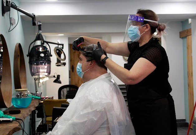 Una peluquera con un cliente en Santander en el día de ayer, en la conocida como fase 0 de la desescalada. / josé Ramón