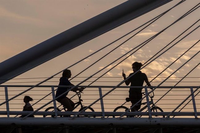 Dos jóvenes montan en bicicleta este martes en la pasarela Jorge Manrique de Murcia.  EFE/Marcial Guillén