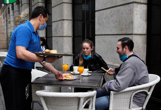Dos jóvenes son atendidos en la mañana de hoy por un camarero en Santander. / J. Ramón