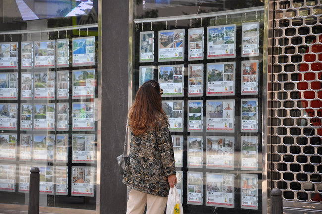 Una mujer observa las ofertas inmobiliarias en la calle José María Pereda, Torrelavega. / S.D.
