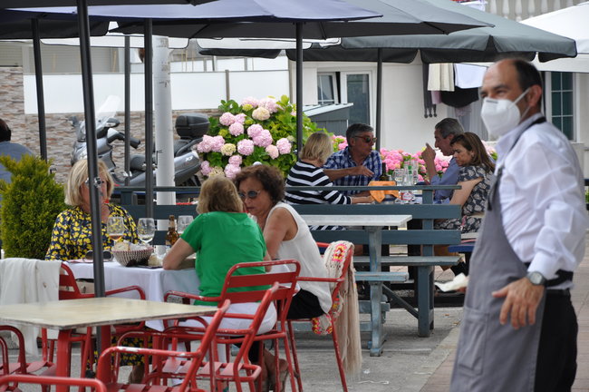 Un camarero con mascarilla sale a atender a los clientes en una terraza del restaurante La Darsena, Suances (Cantabria). / S.D.