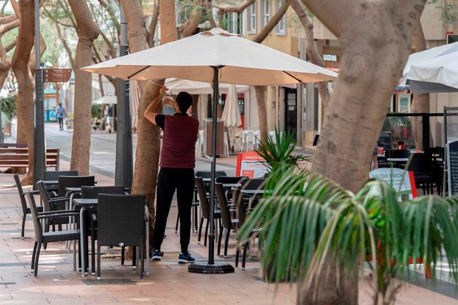 Un camarero coloca una sombrilla en una terraza de un bar. EFE/Miguel Barreto/Archivo