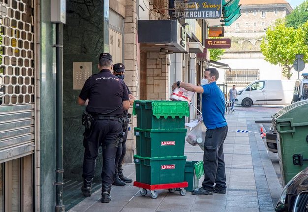 Miembros de la Policía Nacional hablan con un repartidor mientras montan guardia frente al edificio en la calle Nicolás Salmerón de Santander. / EFE/ROMÁN G. AGUILERA