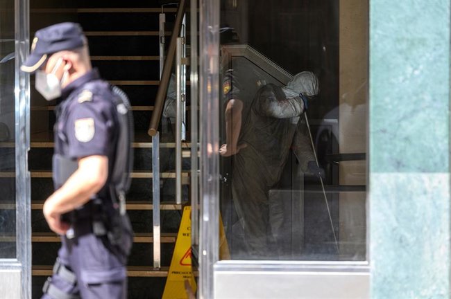 Un hombre desinfecta este martes el portal del edificio de Santander en la calle Nicolás Salmerón. EFE/Pedro Puente Hoyos