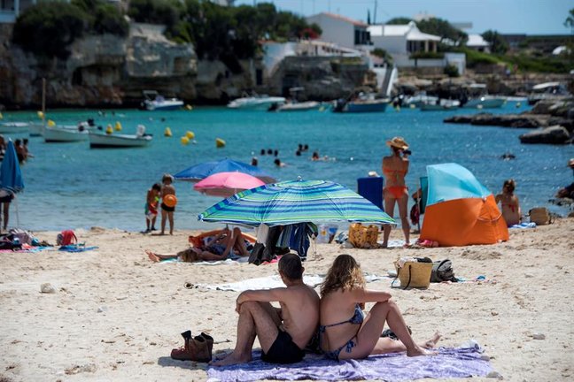 Varias personas disfrutan del sol y del agua en la cala de Alcalfar, Menorca, donde desde el mediodía se ha activado la alerta amarilla por calor.EFE/ David Arquimbau Sintes