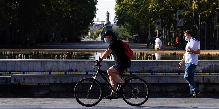 Un hombre circula en bicicleta y con mascarilla por el centro de la ciudad de Valladolid donde este viernes las temperaturas superarán los 35 grados centígrados. EFE/ Nacho Gallego