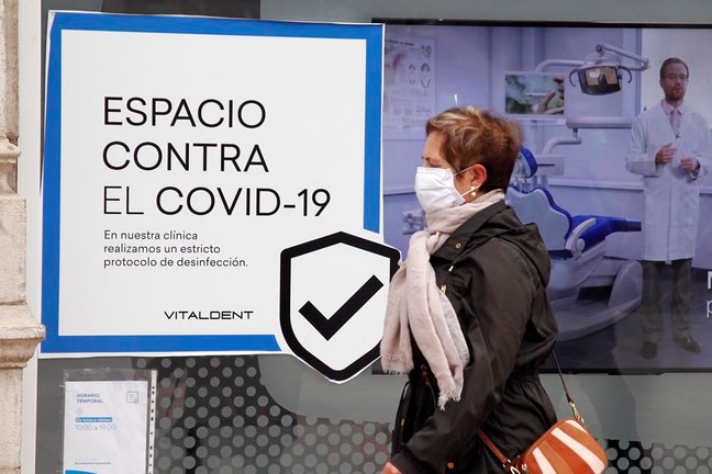 Una mujer pasa por delante de un cartel de una clinica dentista en Santander. / J.R.