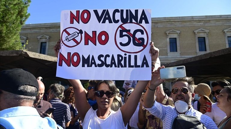 Una manifestante sostiene una pancarta contra la vacuna, contra las mascarillas y contra el 5G durante la protesta de este domingo en Madrid. / JAVIER SORIANO (AFP)