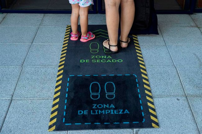 Una madre y su hija se limpian los zapatos durante la reapertura de una escuela infantil en Madrid. EFE/ Rodrigo Jiménez/Archivo