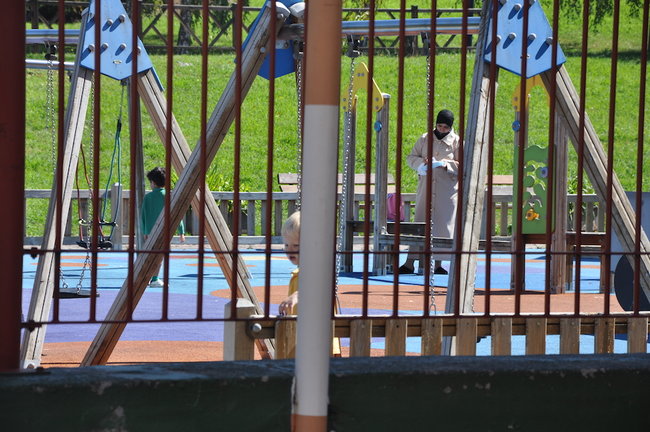 Una madre juega con su hijo en el parque junto al CEIP José María Pereda en Torrelavega. / S.D.
