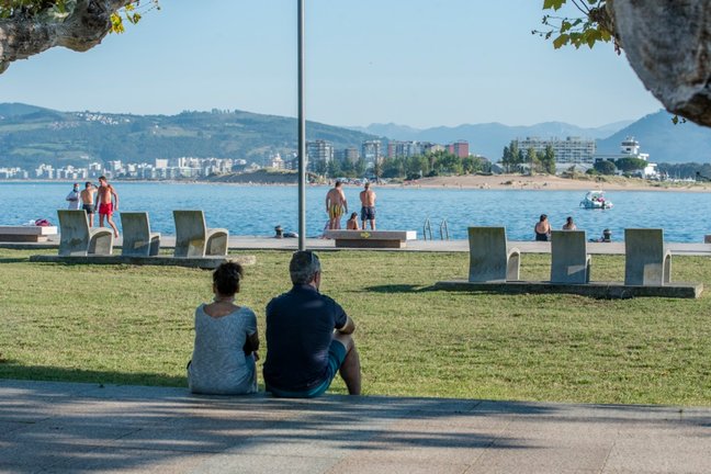 Dos personas sentados junto al paseo en Santoña, Cantabria. / Reguera