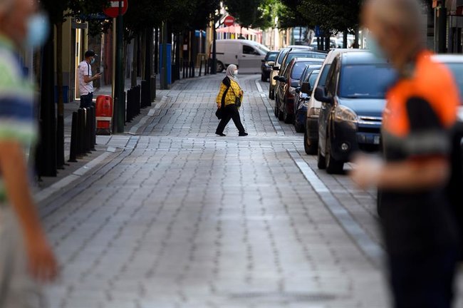 Varias personas caminan por una calle del barrio de La Inmobiliaria en la ciudad cántabra de Torrelavega, a raíz del brote detectado tras dos fiestas en las que se habrían reunido un centenar de personas. EFE/Pedro Puente Hoyos