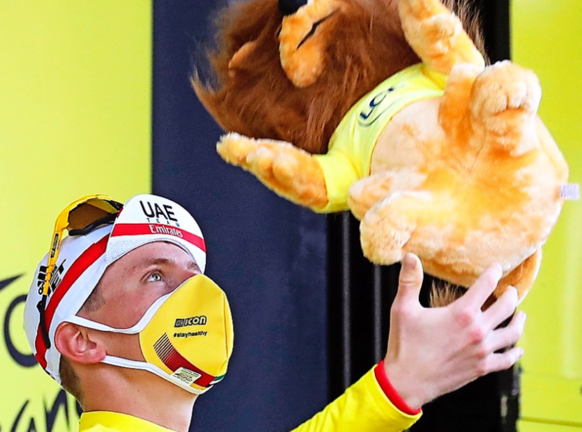 Tadej Pogacar lanza al aire la mascota del Tour tras enfundarse el maillot amarillo. / EFE