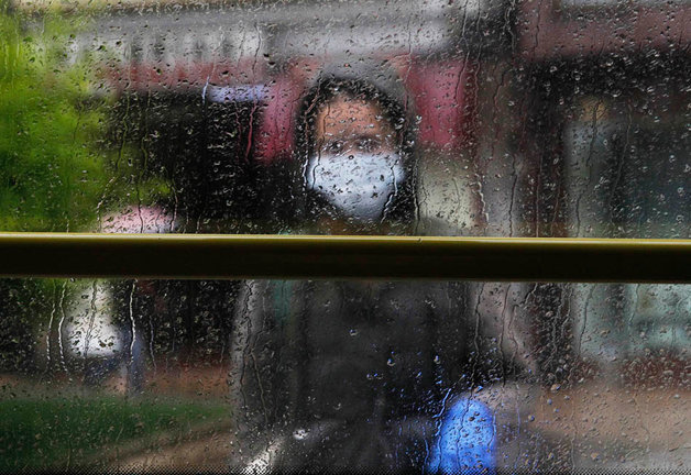 Una persona con mascarilla y guantes espera al autobús en una parada en Santander. / J.R.