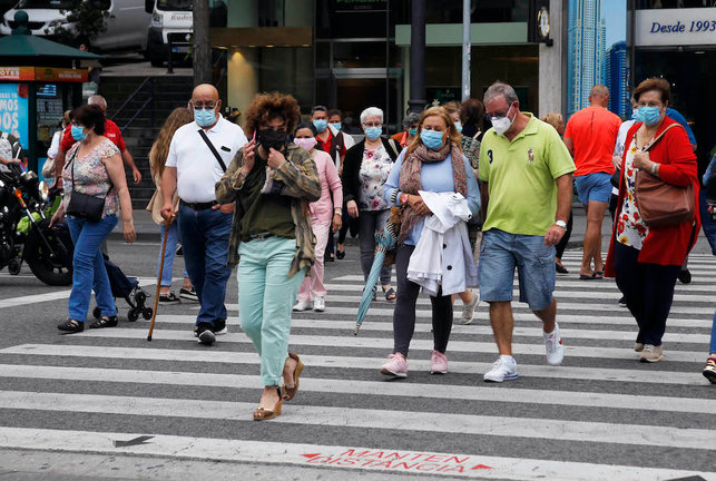 Varias personas cruzan una calle en Santander con su mascarilla puesta. / J. R.