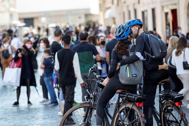 Una pareja se besa mientras centenares de turistas con mascarilla pasean por Roma. EFE/Massimo Percossi