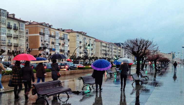 Varias personas caminan por el Paseo Pereda de Santander con sus paraguas. / eltomavistasdesantander
