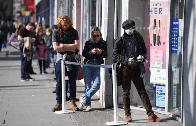 La gente mantiene medidas de distanciamiento social mientras hacen cola para una tienda en Londres, Gran Bretaña. EFE/EPA/NEIL HALL/Archivo