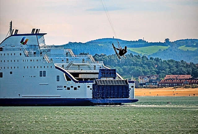 Un &#39;kitesurfer&#39; practica al paso de un ferry en la bahía de Santander, este lunes. EFE/ROMÁN G. AGUILERA