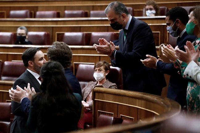 El líder de Vox, Santiago Abascal (i) es aplaudido por su bancada tras su intervención en la moción de censura de su partido al gobierno de coalición en el Congreso de los Diputados este miércoles. EFE/Mariscal