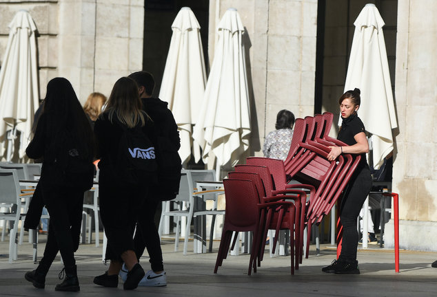 Una joven dependienta prepara las sillas y mesas para atender a los clientes de Santander. / Alerta