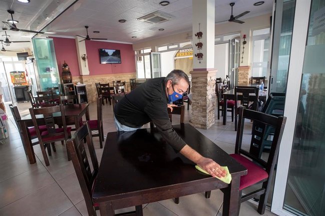 Un camarero limpia una mesa de un restaurante vacío en La Manga del Mar Menor. / EFE