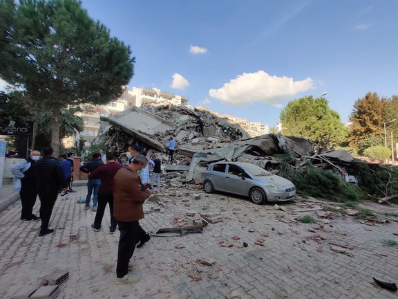 Varias personas cerca de un edificio derrumbado después del terremoto en Esmirna. / EFE
