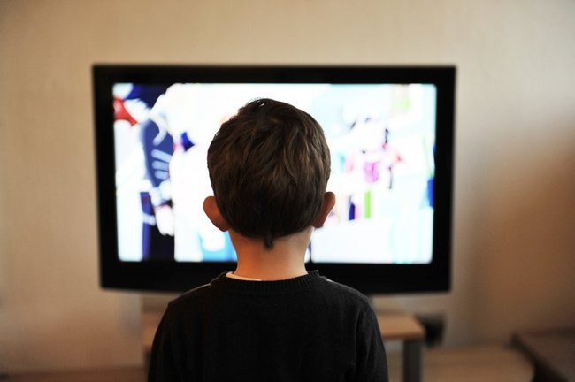 Un niño observa con detenimiento el televisor de su hogar. / ARCHIVO