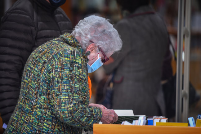 Una persona de avanzada edad ojea un libro en una librería de Santander. / HARDY