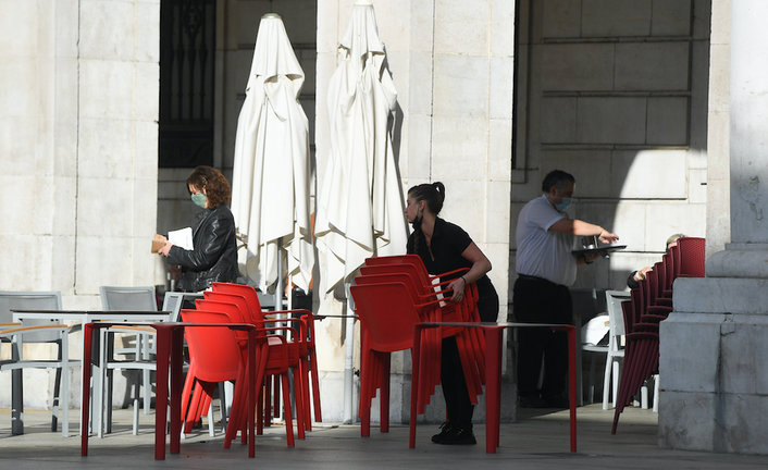 Una trabajadora del sector servicios prepara las mesas en la plaza Porticada de Santander. / HARDY