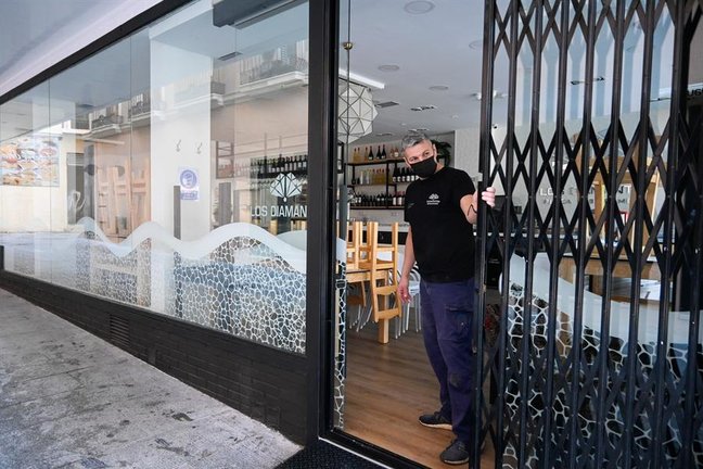 Un empleado cierra la persiana de un bar en el centro de la capital granadina. EFE/Miguel Ángel Molina/Archivo