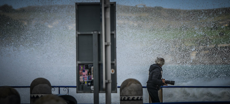 Un fotógrafo se aparta tras romper una ola en el paseo cerca de la playa del Sardinero. / HARDY