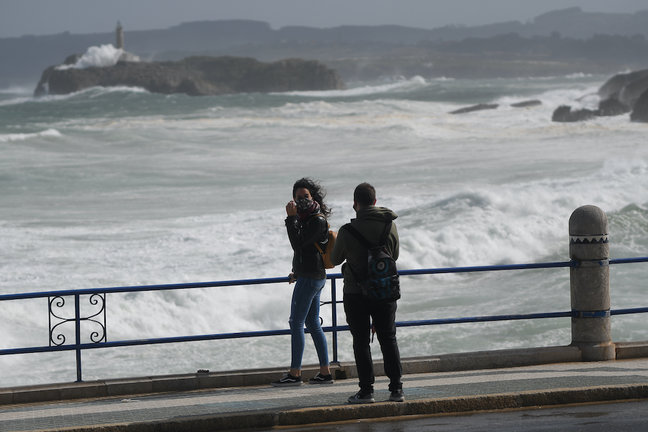Dos personas se hacen una foto junto a la costa de la playa del Sardinero, Santander. / Hardy