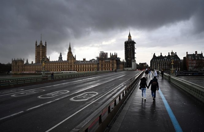 Varias personas cruzan el puente de Westminster, este lunes en Londres (Reino Unido), cuando las autoridades británicas se están planteando un nuevo cierre de tiendas de ropa, bares y restaurantes en la capital ante el nuevo repunte de positivos por coronavirus. EFE/ Andy Rain