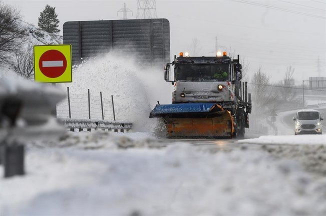 Una máquina quitanieves limpia la A-67 tras una nevada por la que varios camiones permanecen en un atasco este sábado en la localidad cántabra de Arenas de Iguña. EFE/Pedro Puente Hoyos
